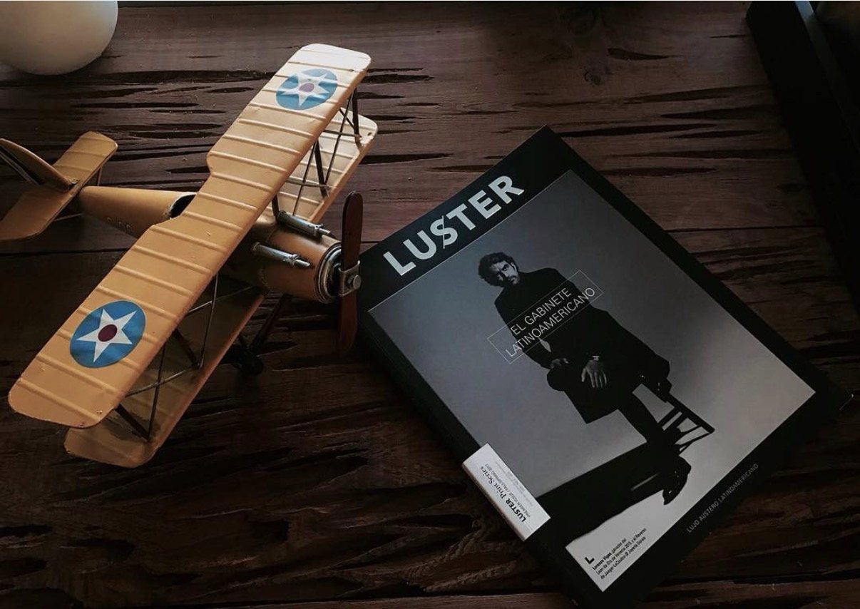 Luster Magazine resting on a dark wood table