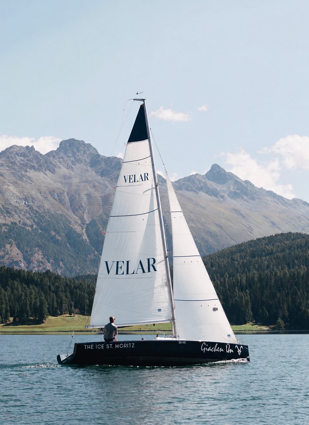 Sailing boat on an alpine lake beneath the mountains