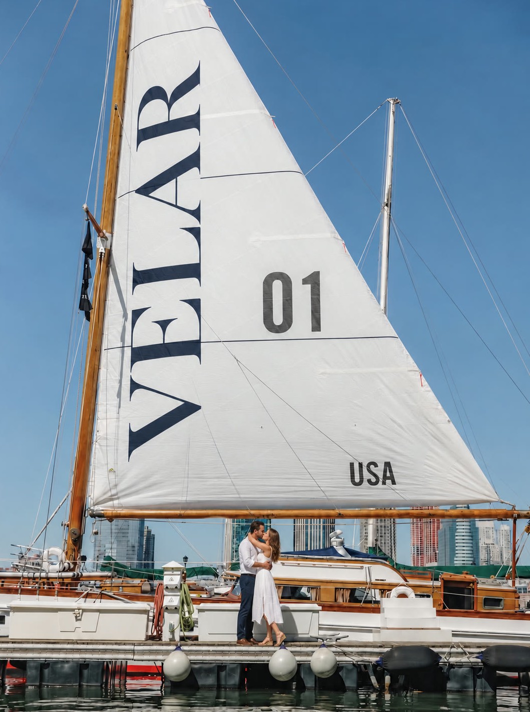 Guests on the dock beside a large white sail